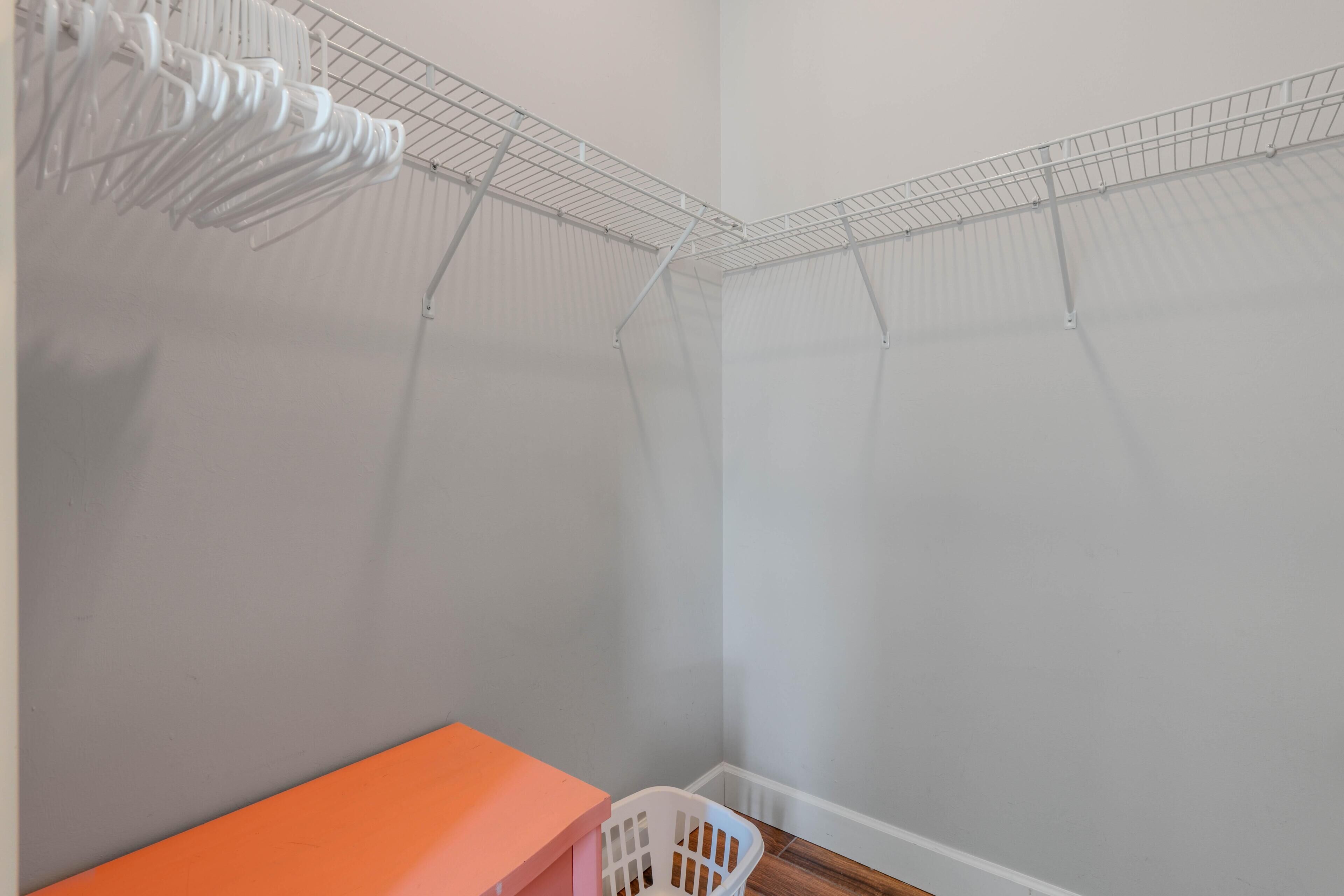 Een hoek van een ruimte met een witte muur, een metalen rek en een witte plastic stoel.