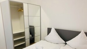 A hotel room with a bed, white linens, a wardrobe with a mirror, and two pillows. - Modern vacation home in the countryside and close to the city! (Koblenz)