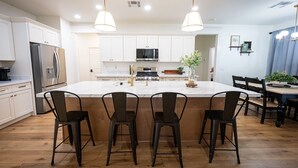 A modern kitchen with white cabinets, stainless steel appliances, and a central island with bar stools.