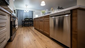 A modern kitchen with wooden cabinets, stainless steel appliances, and a wooden floor.