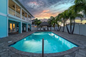 A swimming pool with a tiled edge, surrounded by a patio area with chairs and a table. - Crain's Perch (Fort Myers Beach)