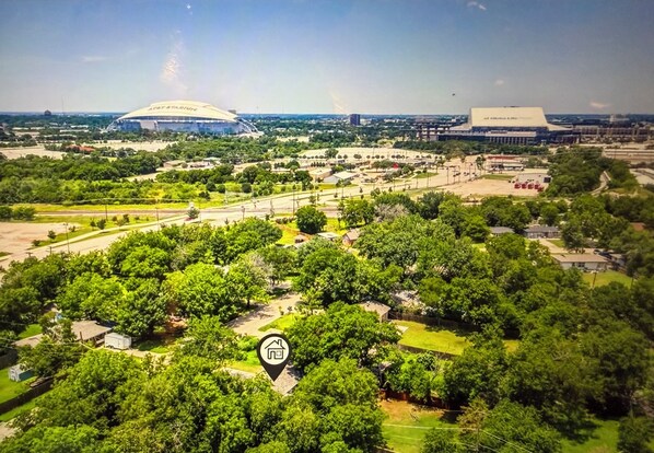 Luchtbeeld van een stadioncomplex met meerdere gebouwen, waaronder een groot stadion en een kleinere accommodatie. Er zijn groene zones met bomen en paden.