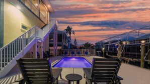 A poolside area with a staircase, lounge chairs, and a view of the sky. - Drift Inn (Fort Myers Beach)