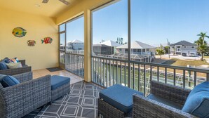 A balcony with wicker furniture, a ceiling fan, and a view of neighboring houses. - Drift Inn (Fort Myers Beach)