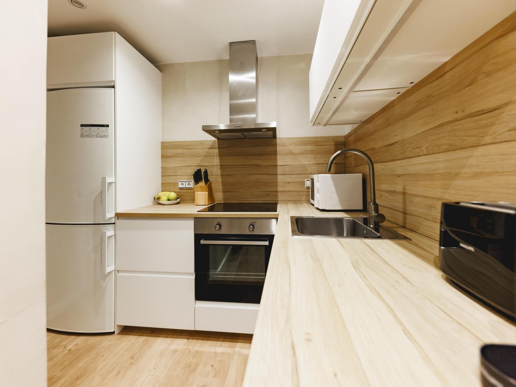 Eine kompakte Küche mit Kühlschrank, Backofen, Spüle und Mikrowelle.