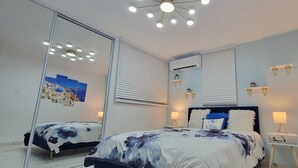 A bedroom with a bed, bedside lamps, a ceiling light, and wall-mounted air conditioning units. - Villa Santorini 3-bedroom apartment in welcoming Bayamón with WiFi, AC. Enjoy  (Bayamón)