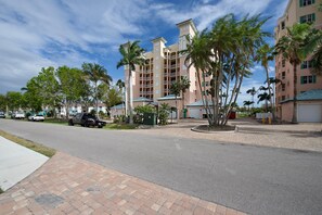 A multi-story hotel with a central courtyard, palm trees, and a paved walkway. - Palm Harbor #602 (Fort Myers Beach)