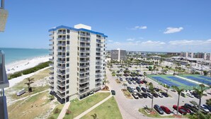 A high-rise hotel with multiple balconies, a parking lot, and a beach view. - Estero Beach & Tennis 901-c (Fort Myers Beach)