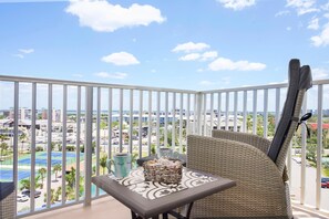Enjoy a serene view of the tennis court from this balcony, complete with a wicker chair and small table.