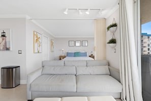Um quarto moderno com uma cama grande, um sofá e uma lixeira.