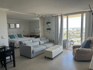Relax in this stylish living room with a large sofa, dining area, and balcony offering city views.