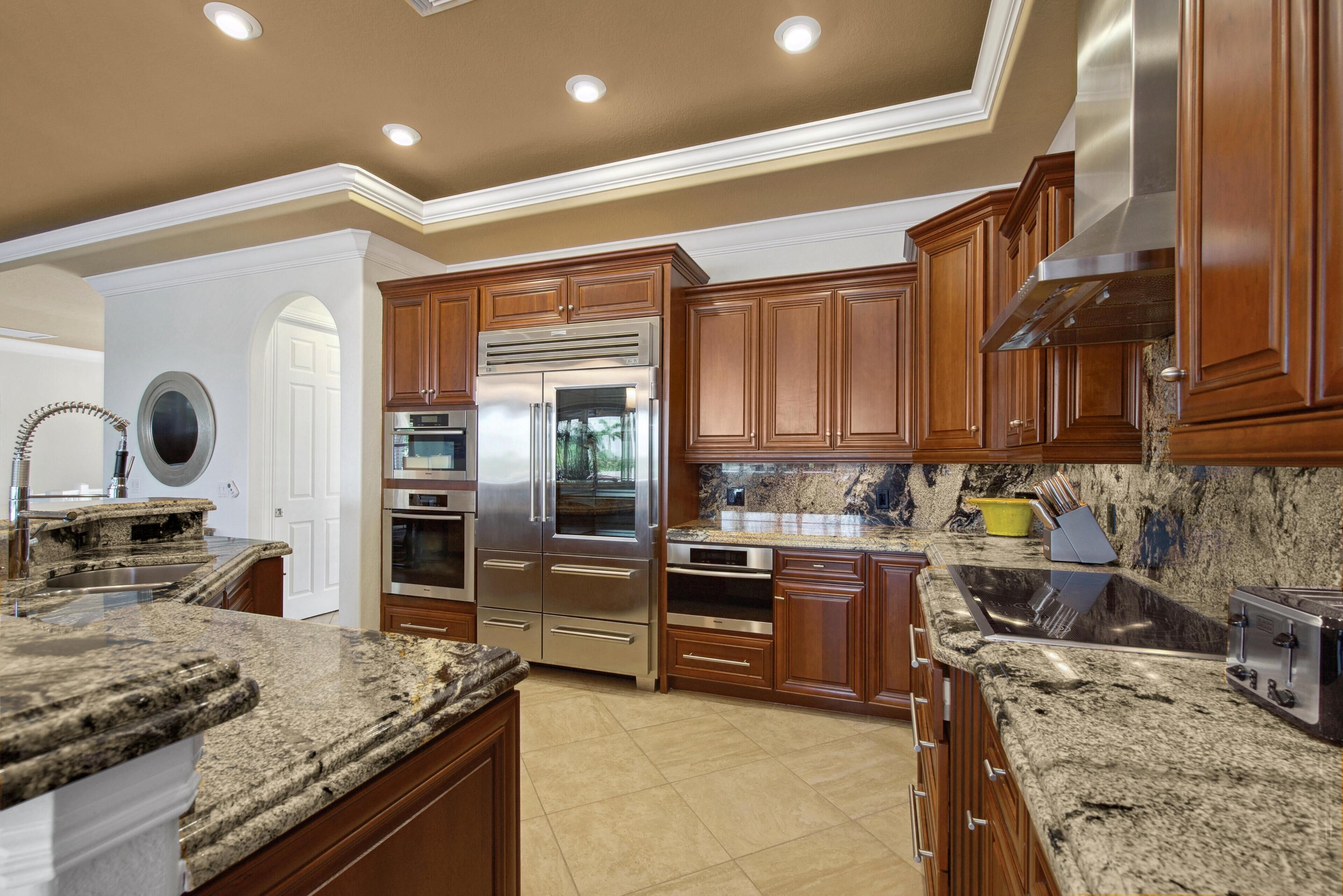 A kitchen with granite countertops, stainless steel appliances, wooden cabinets, and a built-in oven.