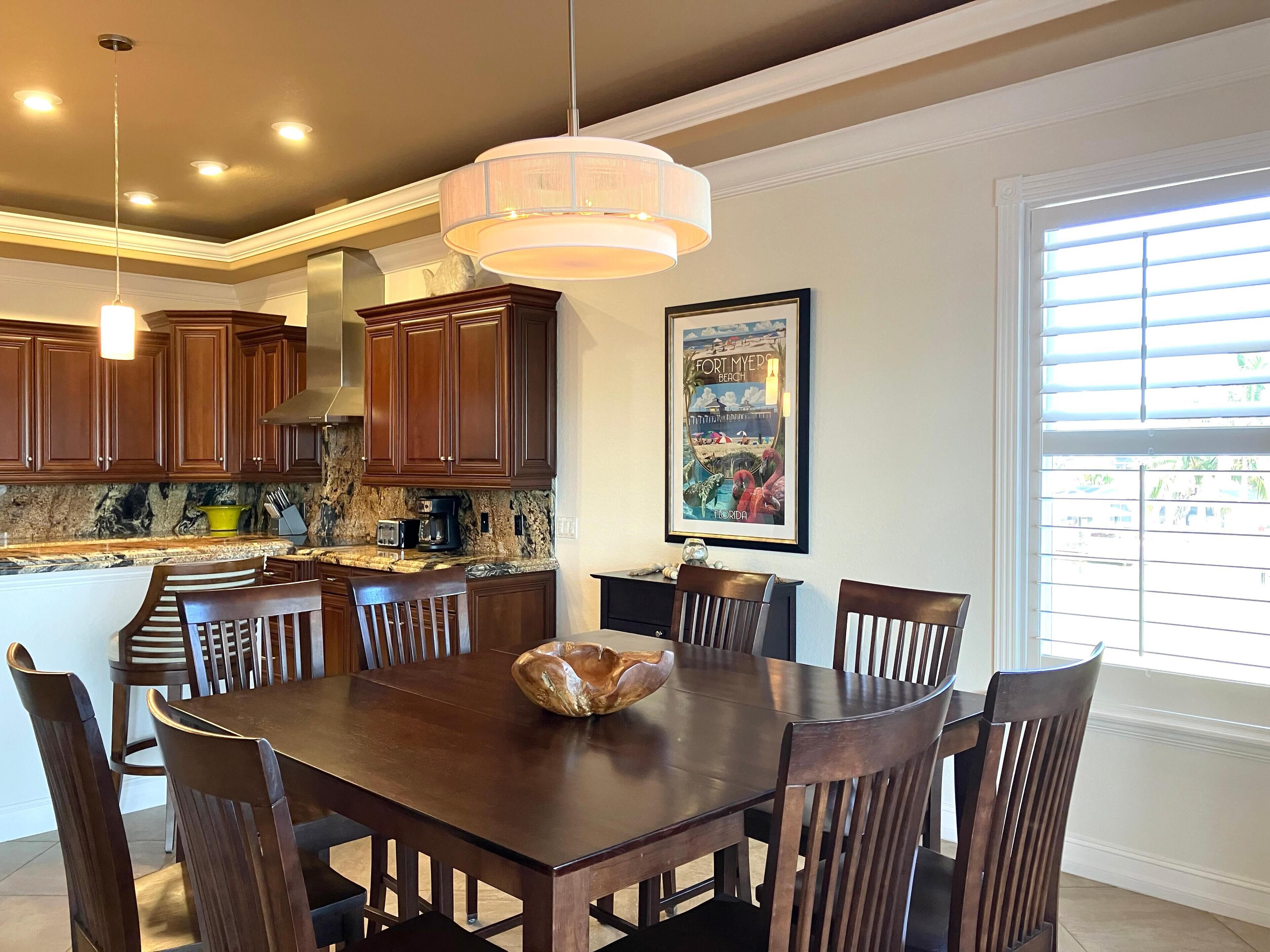 A kitchen with wooden cabinets, a granite countertop, and a dining table with chairs.