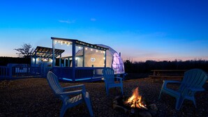 A dome-shaped structure with a glass enclosure and a fire pit in the foreground.