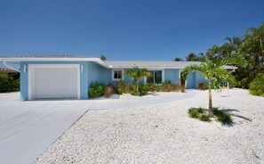 Stroll through the beautifully maintained front yard, featuring a variety of plants and a palm tree.