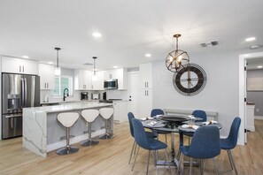 Enjoy cooking in this kitchen with a central island, bar stools, stainless steel appliances, and a sleek countertop.