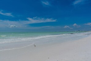 Una playa con cielos despejados y aguas tranquilas.
