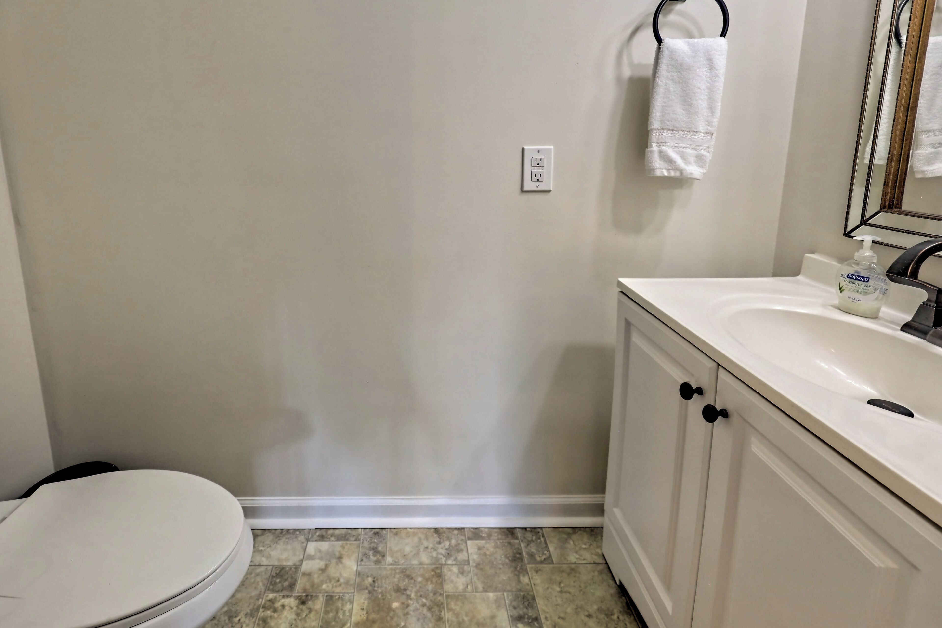 A bathroom with a toilet, a sink, and a mirror.