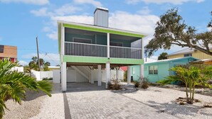 A two-story building with a green and white exterior, a covered entrance, and a balcony.
