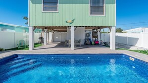 A two-story house with a swimming pool in front.