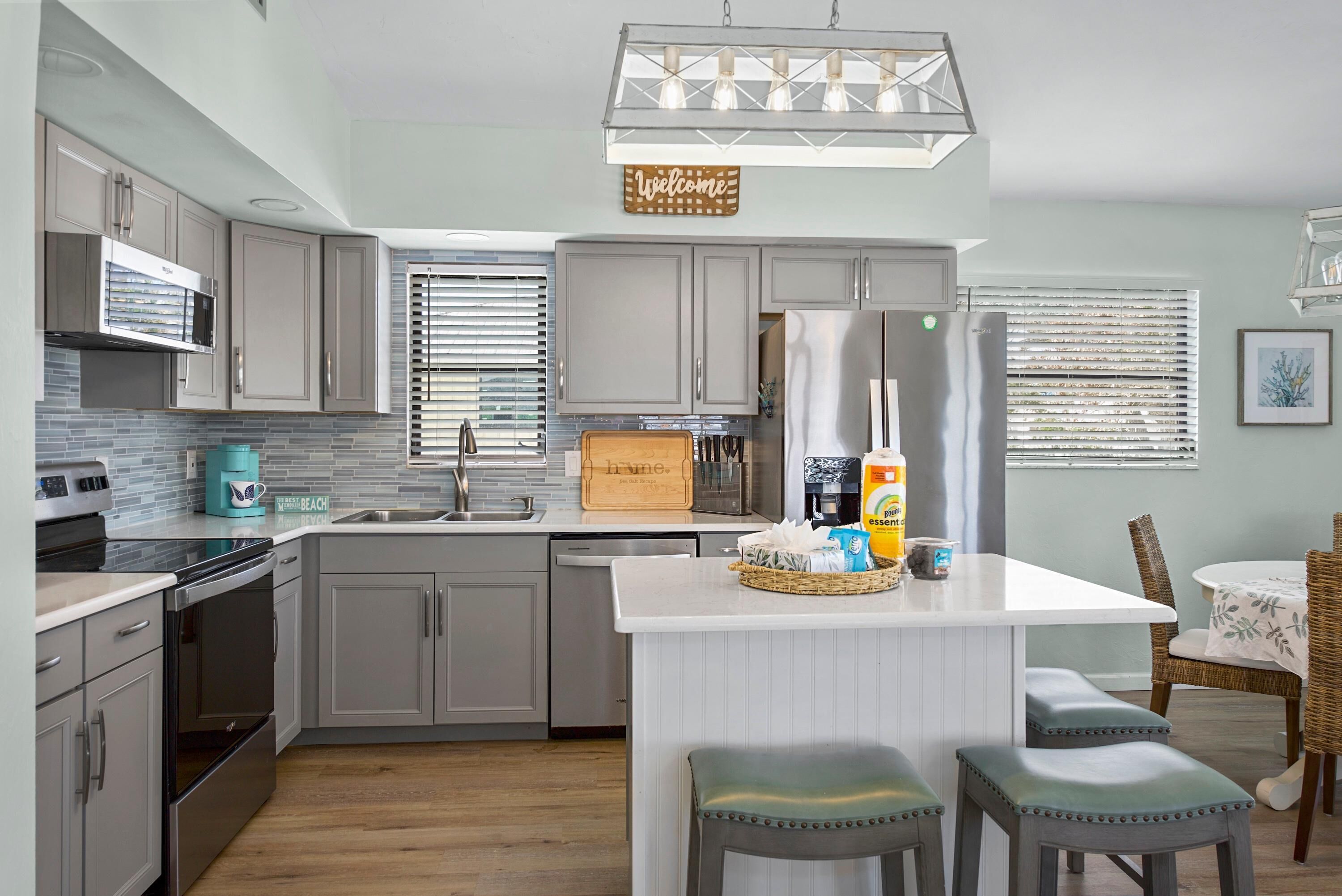 A modern kitchen with grey cabinets, a central island, and a built-in oven.