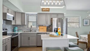 A modern kitchen with grey cabinets, a central island, and a built-in oven.