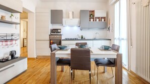 A modern kitchen with a dining area, featuring a built-in oven, microwave, and gas stove.