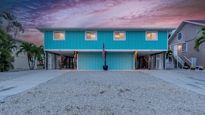 A two-story building with a flat roof, a covered front porch, and a flagpole. - Endless Tides 2 (Fort Myers Beach)