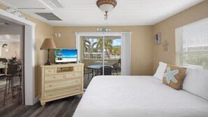 A bedroom with a bed, a dresser, a television, and a balcony with a view.