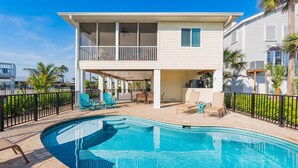 A two-story house with a pool, outdoor furniture, and a fenced patio area. - Island Breeze (Fort Myers Beach)
