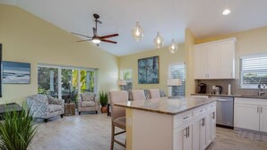 A spacious kitchen with a central island, white cabinetry, and a ceiling fan. - Island Breeze (Fort Myers Beach)