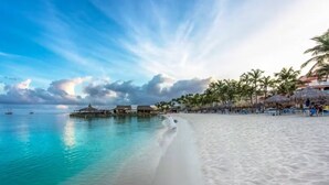 A beach with clear turquoise water, a sandy shore, and overwater bungalows.