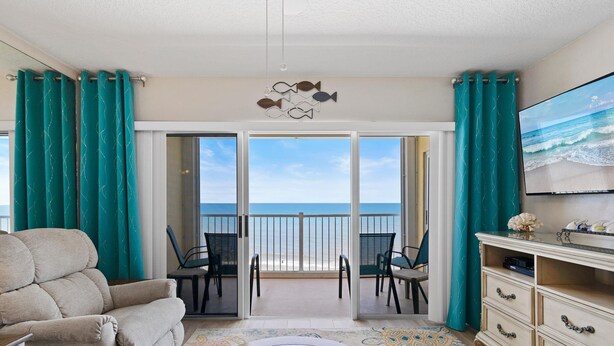 A room with a view of the ocean, a sofa, a TV, and a coffee table. - Ponce de Leon Towers 702 (New Smyrna Beach)