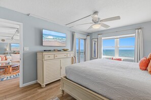 Un dormitorio con cama, cómoda, televisor y vista al océano.