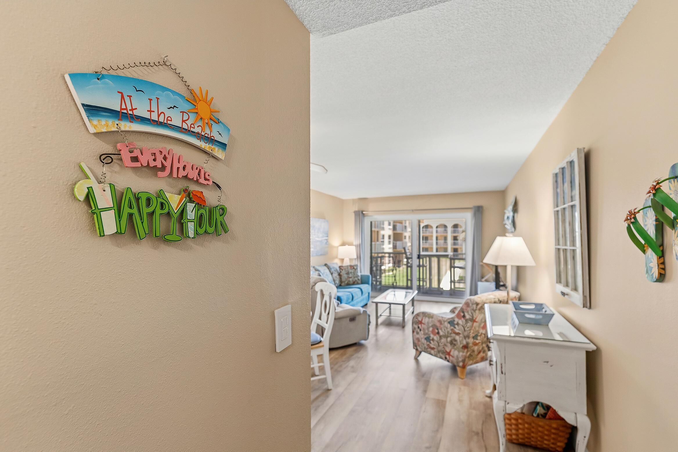 Una habitación con vista al mar, un letrero de playa, un letrero que dice 'Happy Hour' y un comedor con mesa y sillas.