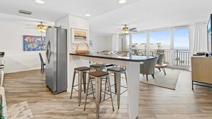 A modern kitchen with a central island, bar stools, and a refrigerator. - Pelican C606 (New Smyrna Beach)