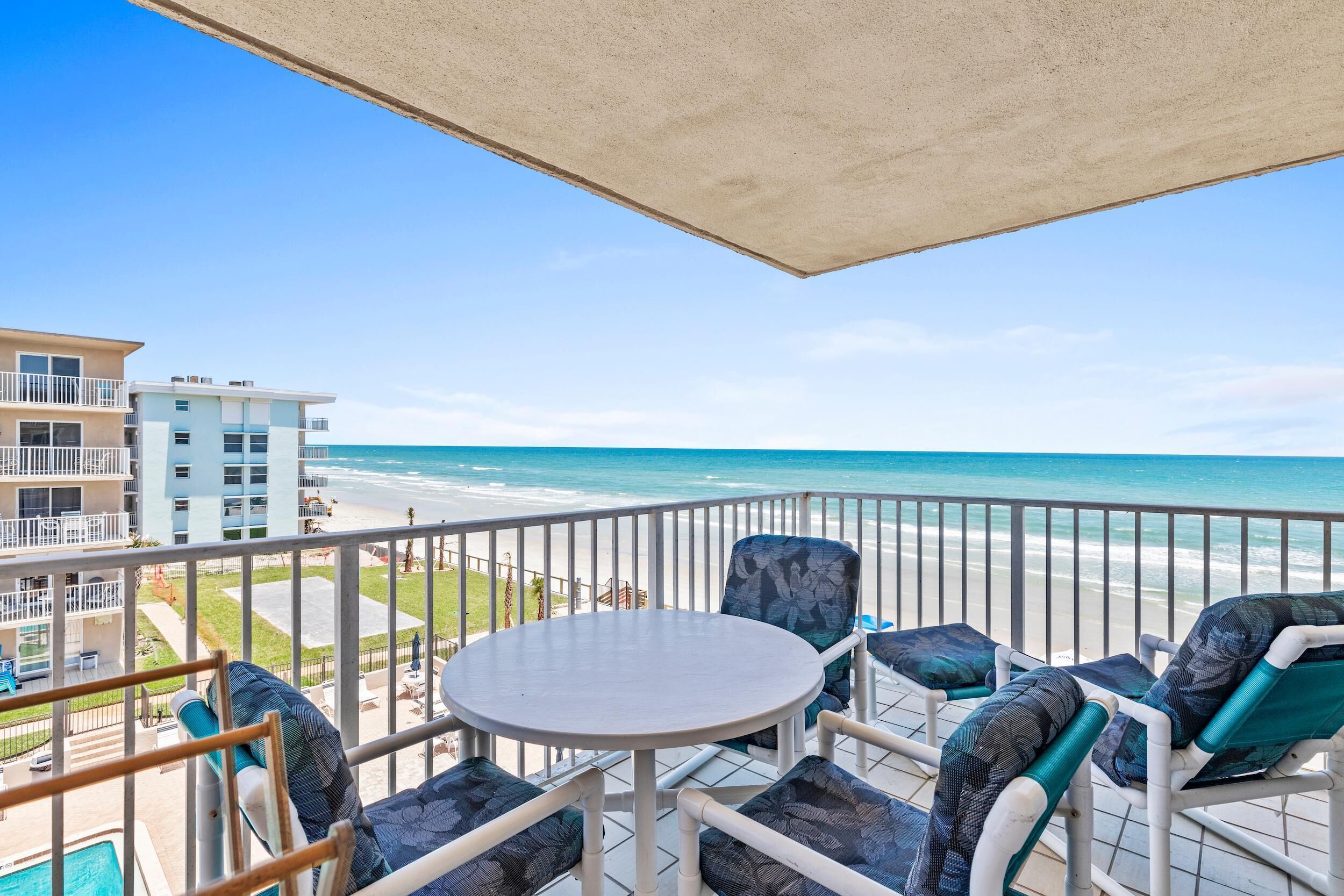 Ein Balkon mit Tisch und Stühlen mit Blick auf einen Strand.