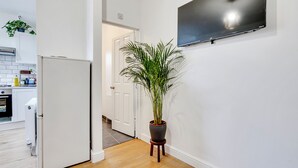 A modern kitchen with white cabinets, a white refrigerator, and a potted plant.