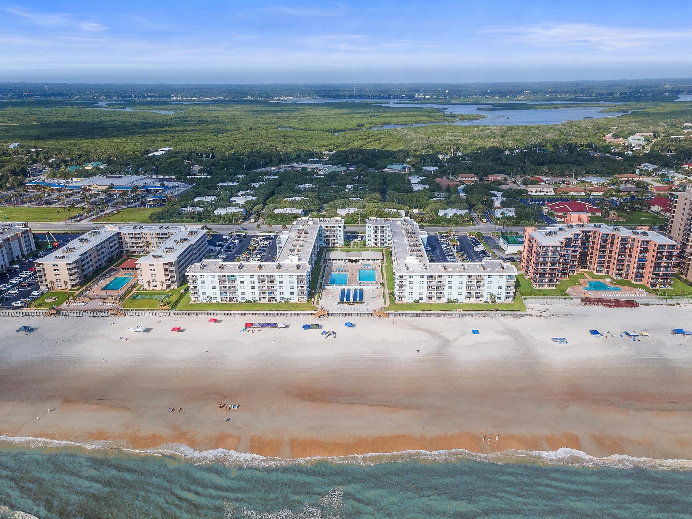 A coastal hotel with multiple buildings, a beach, and a view of the ocean.