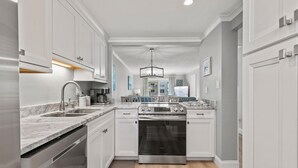 Una cocina moderna con armarios blancos, electrodomésticos de acero inoxidable y encimera de mármol.