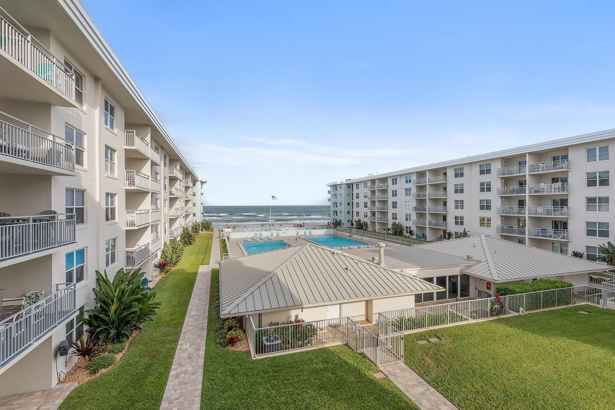 Un hôtel à plusieurs étages, doté de balcons, d’une piscine et offrant une vue sur l’océan.