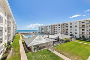 A resort with multiple-story buildings, a swimming pool, and a view of the ocean. - Sea Coast Gardens II 316 (New Smyrna Beach)