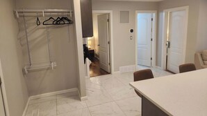 A hotel room with a bathroom, a closet with hanging clothes, a table, and a chair. - beautiful, cozy private and quiet house + heat garage -EV charger - NO BASEMENT (Edmonton)