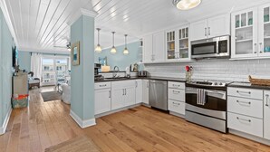 Una cocina moderna con armarios blancos, electrodomésticos de acero inoxidable y piso de madera.