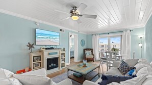 Una sala de estar con televisión, chimenea, comedor y vista al océano.
