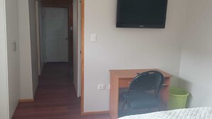 Een hotelkamer met een bureau, stoel en een aan de muur bevestigde televisie.