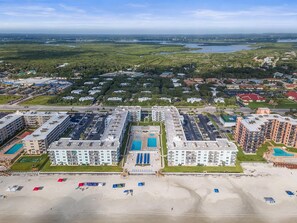 Um hotel à beira-mar com vários edifícios, uma praia e vista para o oceano e a paisagem distante.