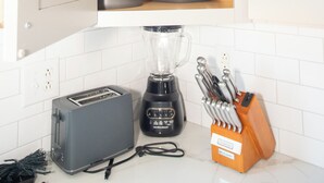 Una cocina con un armario empotrado que contiene utensilios de cocina, un tostador, una licuadora y un bloque de cuchillos.