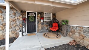 A stone exterior with a black door, a red chair, and a welcome mat. - Welcome to Valley View (Derby)