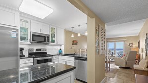 A modern kitchen with white cabinets, stainless steel appliances, and a granite countertop.